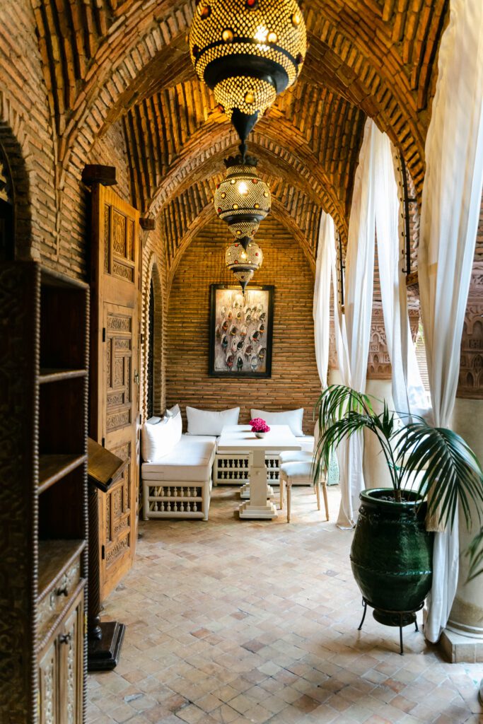 Luxury riad lounge area with potted plants, white fabric, and curtains as seen by a hospitality photographer.