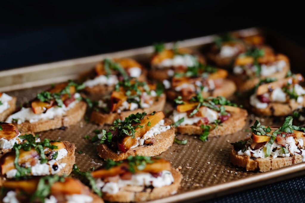 Close up of peach and burrata crostinis on baking sheet